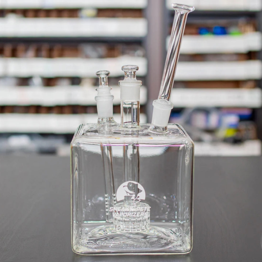 sneaky pete mega cube glass rig with glass mouthpiece and glass plugs sat on grey surface