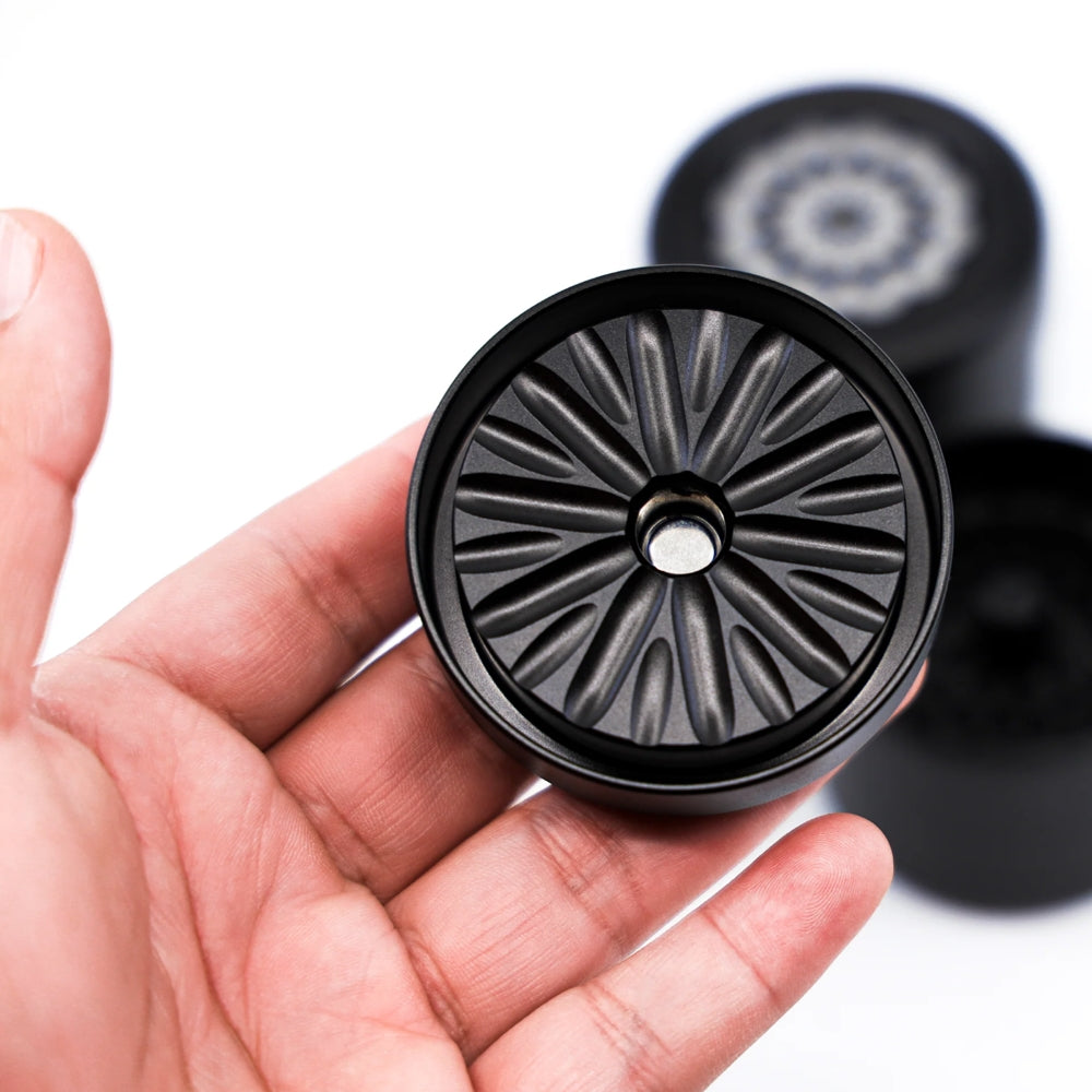 black and grey flowermill 2.5 standard herb grinder with top section in users hand on white background