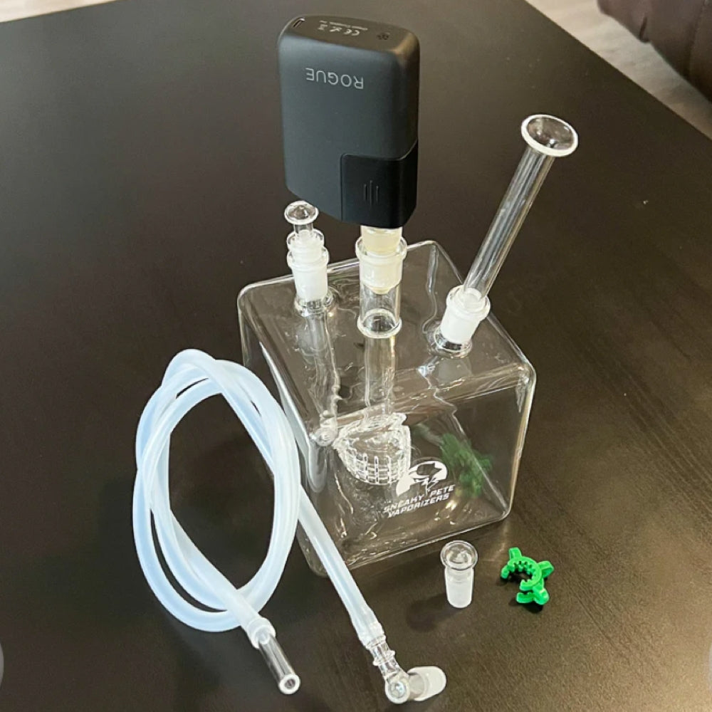 sneaky pete mega cube glass rig paired with healthy rips rogue vaporizer sat on grey surface