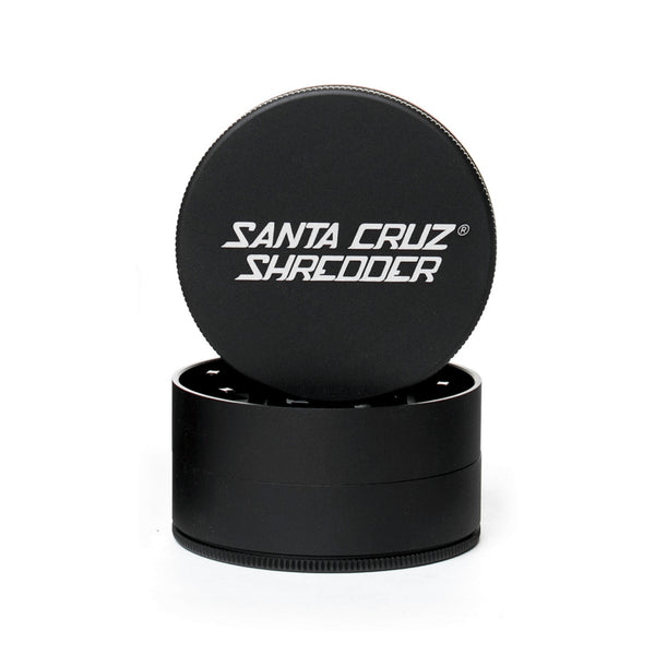 black circular 2 piece herb grinder with the lid section sitting on top of the base. Santa Cruz logo on lid.