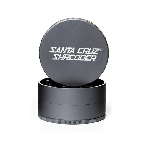Grey circular 2 piece herb grinder with the lid section sitting on top of the base. Santa Cruz logo on lid.